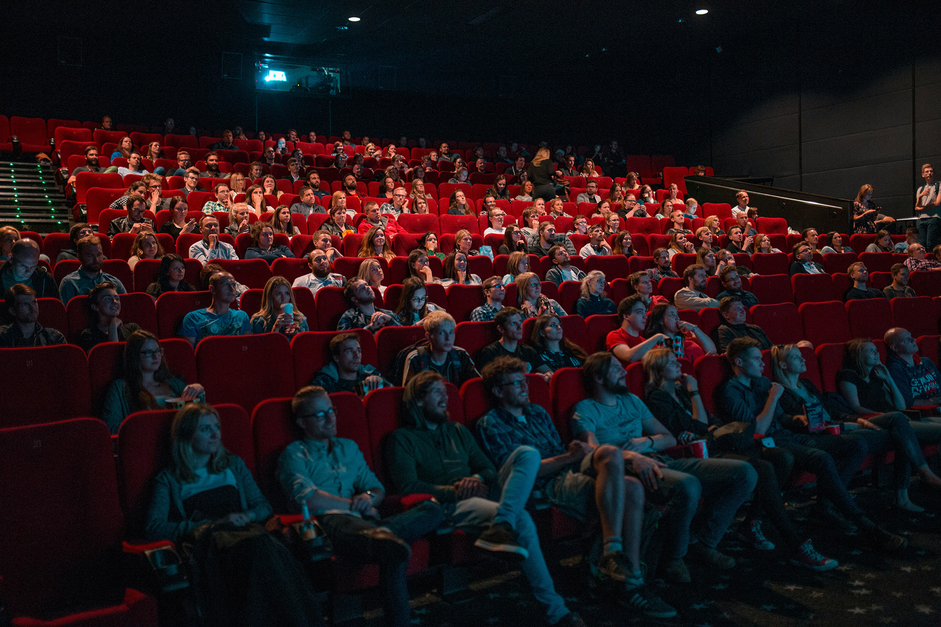 A packed cinema auditorium of fans watching a premiere